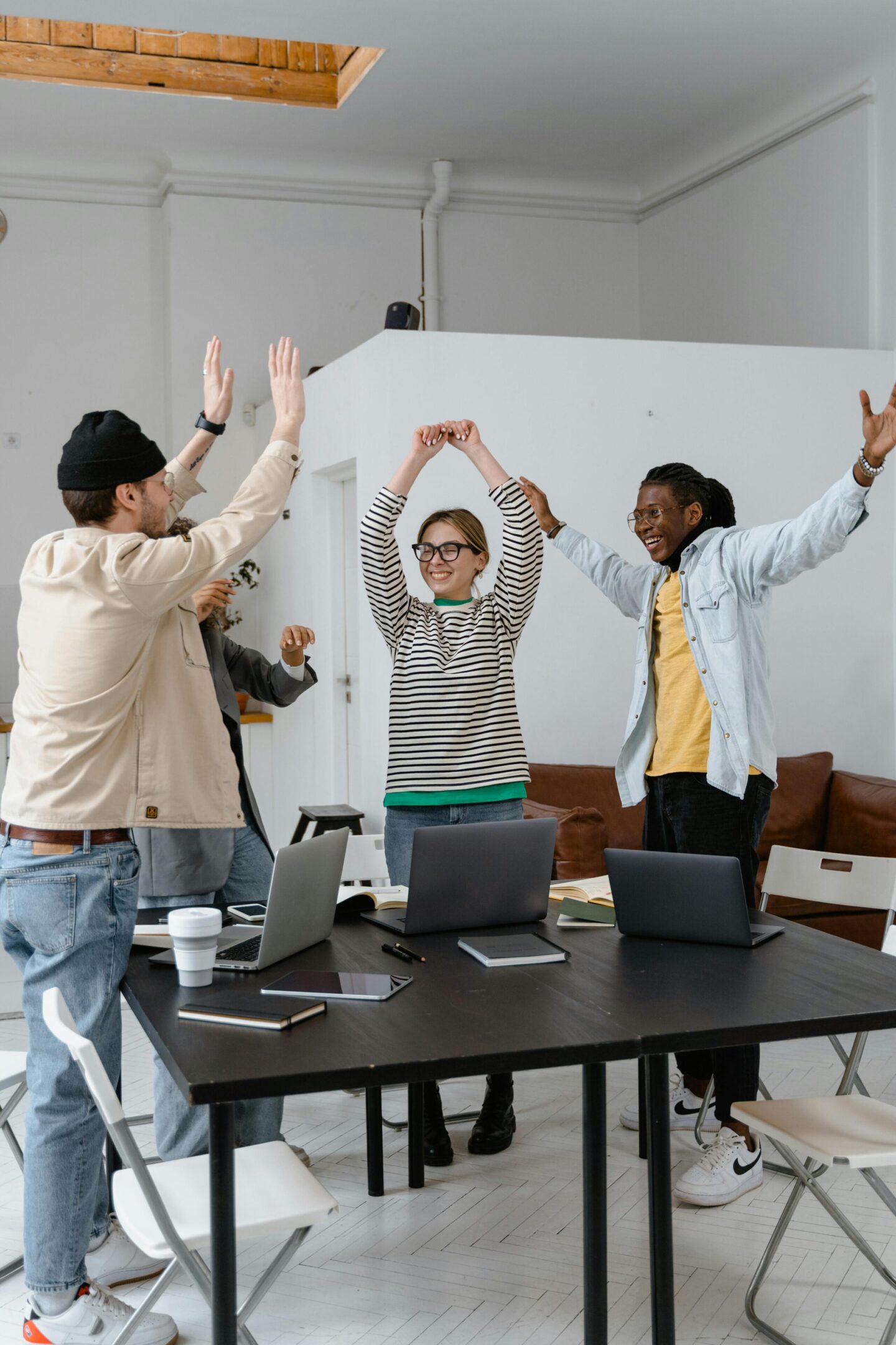 A group of people standing around a table with laptops.